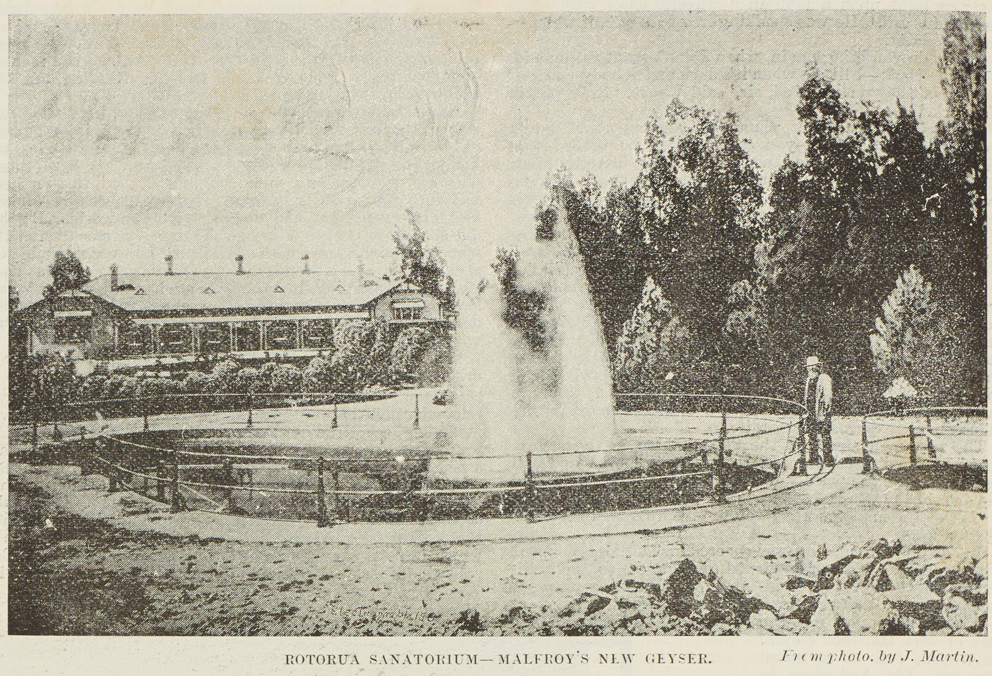 Malfroy's engineered geyser erupting inside a fenced pool in the Sanatorium grounds, two onlookers at the rail, 1891