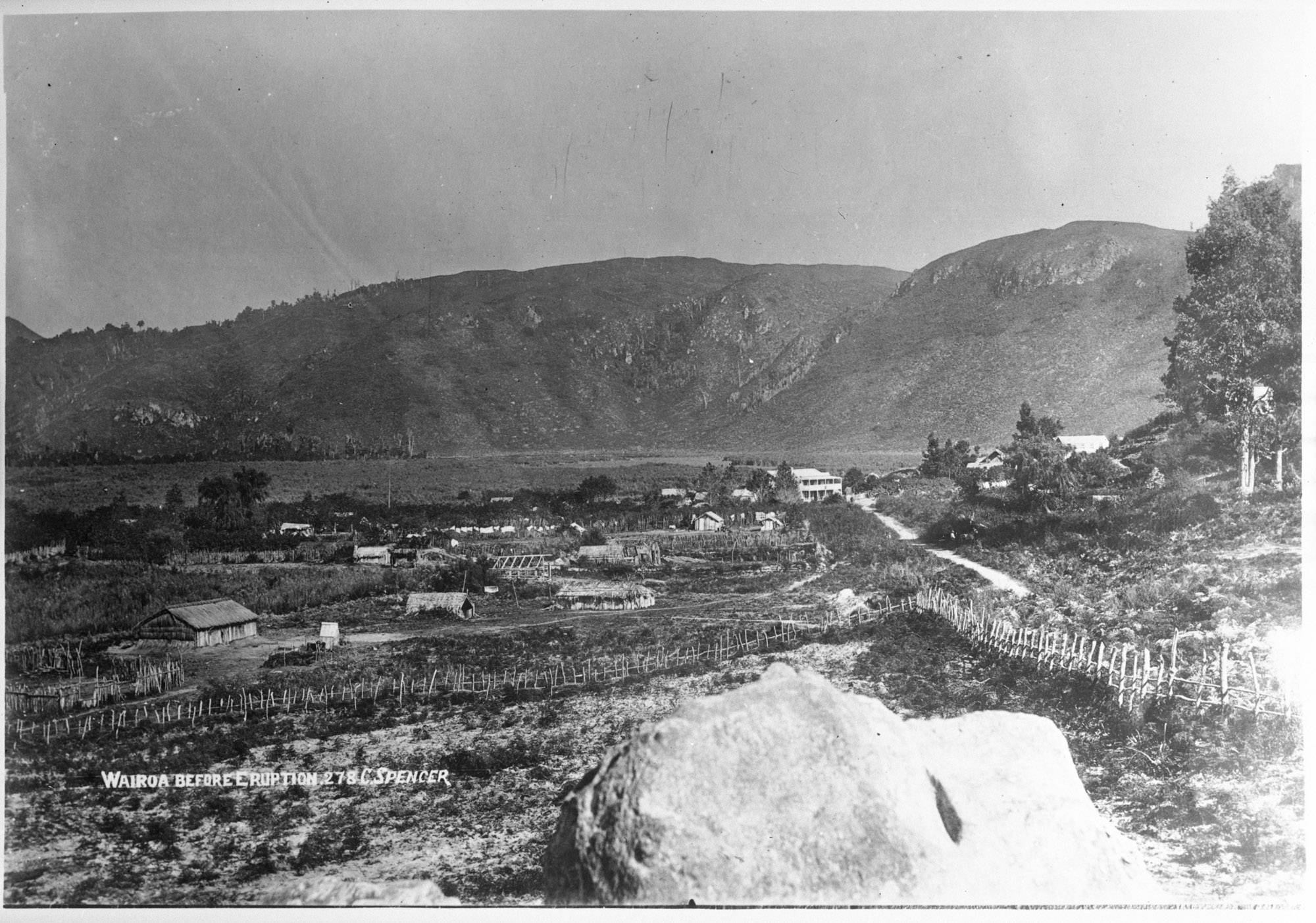 Te Wairoa village before the eruption — whare, fences, the two-storey hotel, with the hills behind