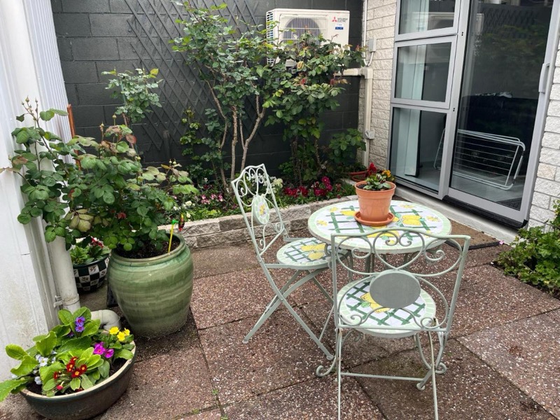 The private courtyard garden — roses, flowering pots and a bistro table in the sun