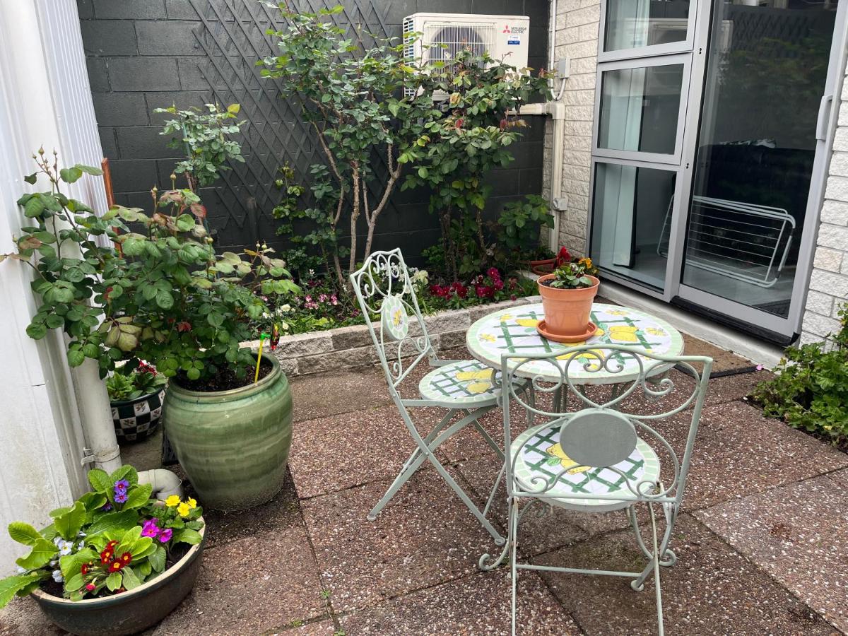 The private courtyard garden — roses, flowering pots and a bistro table in the sun