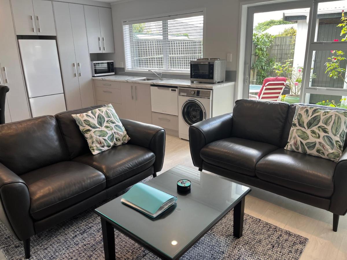 Two leather sofas with leaf-print cushions in the sunlit lounge